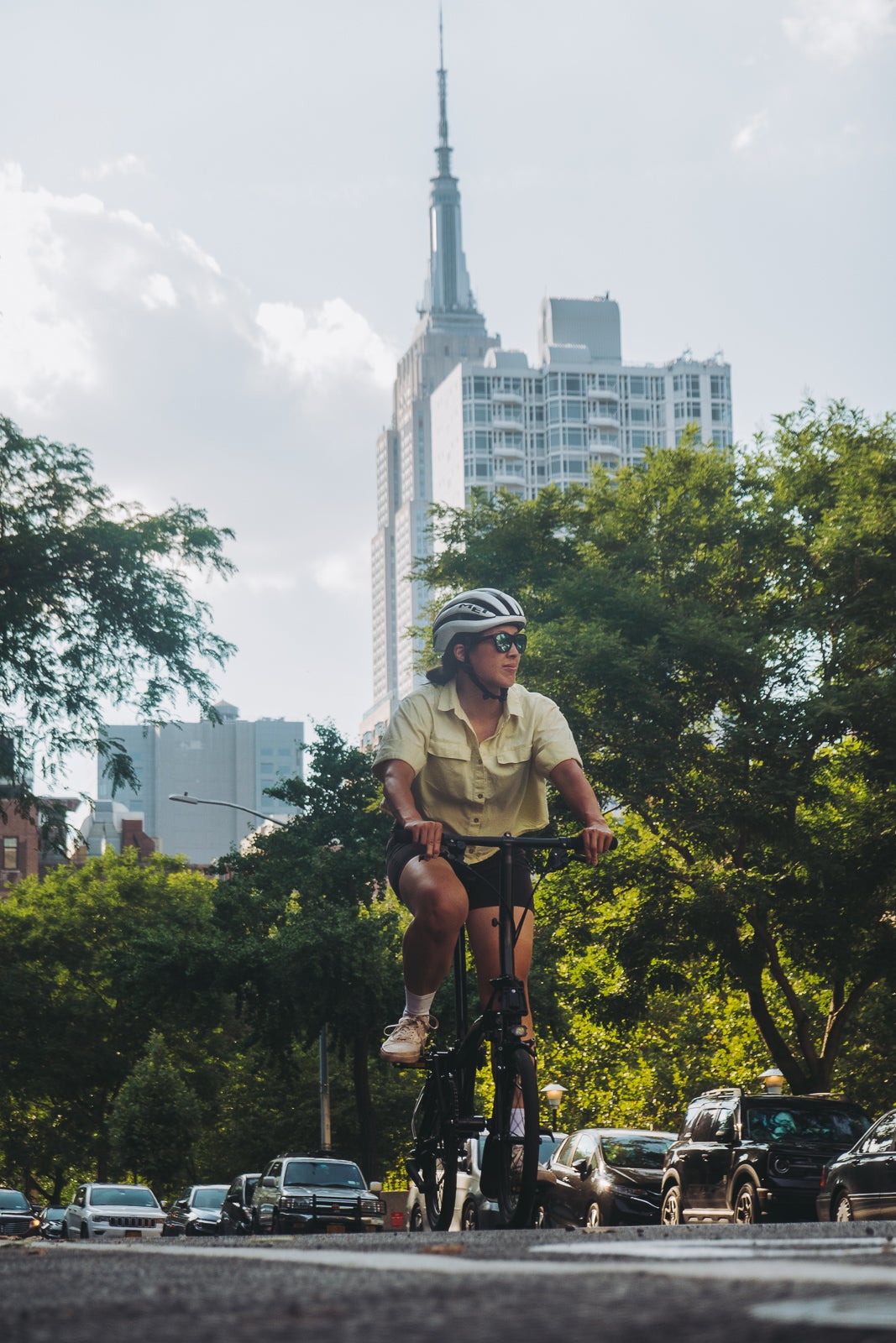 A person cycling through the park on their Brompton with the NYC skyline in the background