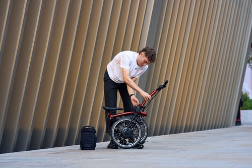 person folding a brompton electric p line in flame lacquer
