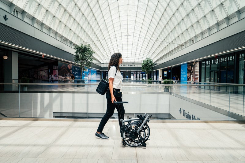 person rolling a brompton electric p line through train station