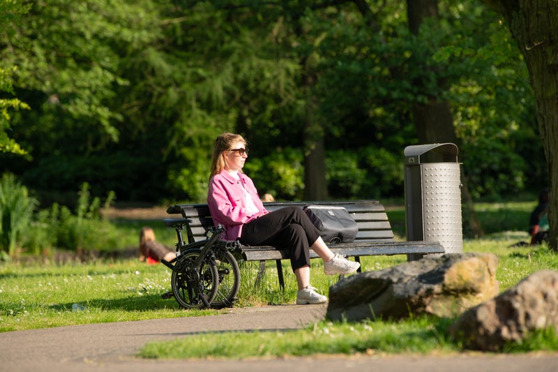 Person sat on bench with folded Brompton bike