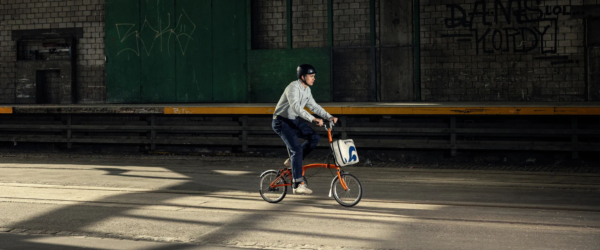 A man riding a Brompton with a Freitag x Brompton bag attached to the luggage block