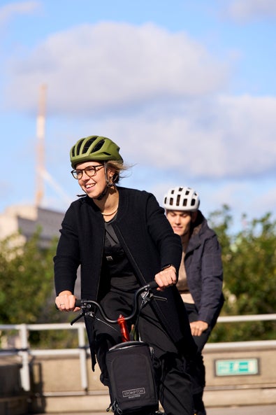 2 people riding electric p line bromptons in helmets and smiling