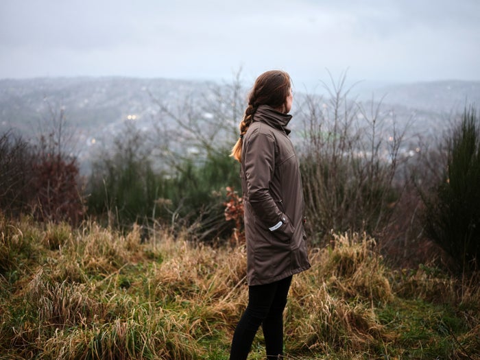 An image of Jess Fawcett in a meadow looking over the countryside wearing the Brompton x Protected Species jacket
