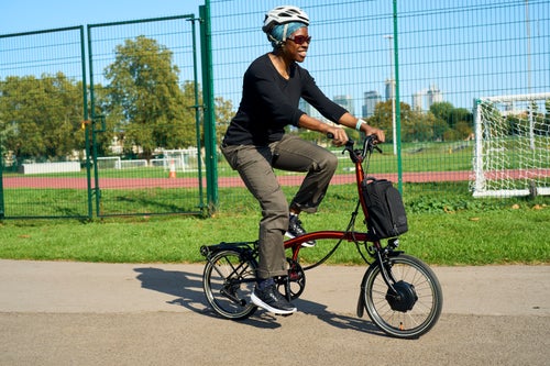 happy person cycling brompton electric p line through park