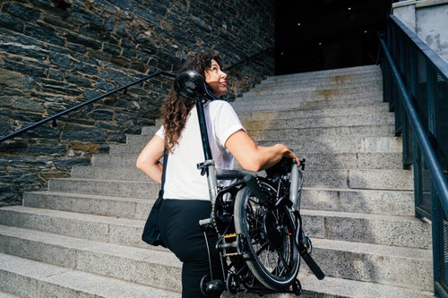 person carrying a brompton p line electric up stairs