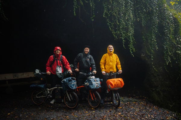 Three people stood in woodland with Brompton bikes