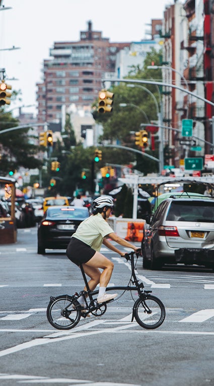 Person cycling across the road in NYC on a Brompton.