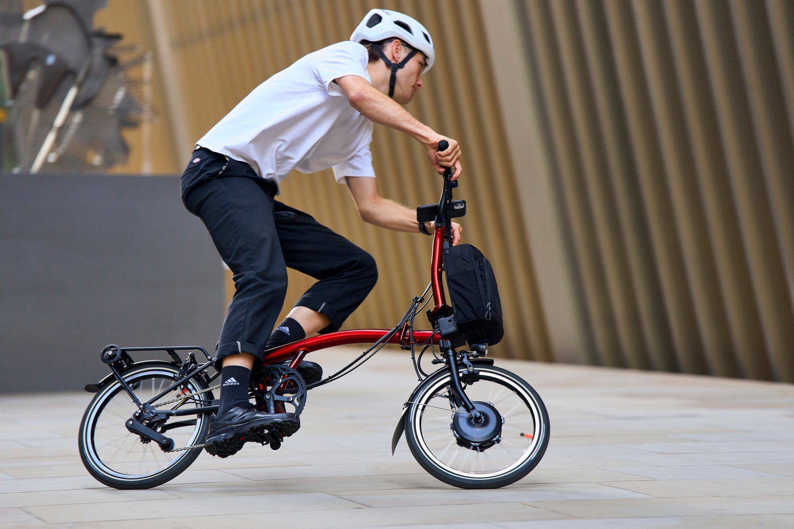 lifestyle image of person riding electric p line brompton in flame lacquer