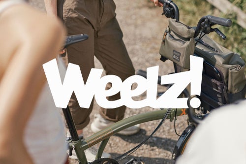 Weelz! logo over image of the brompton bear grylls bike