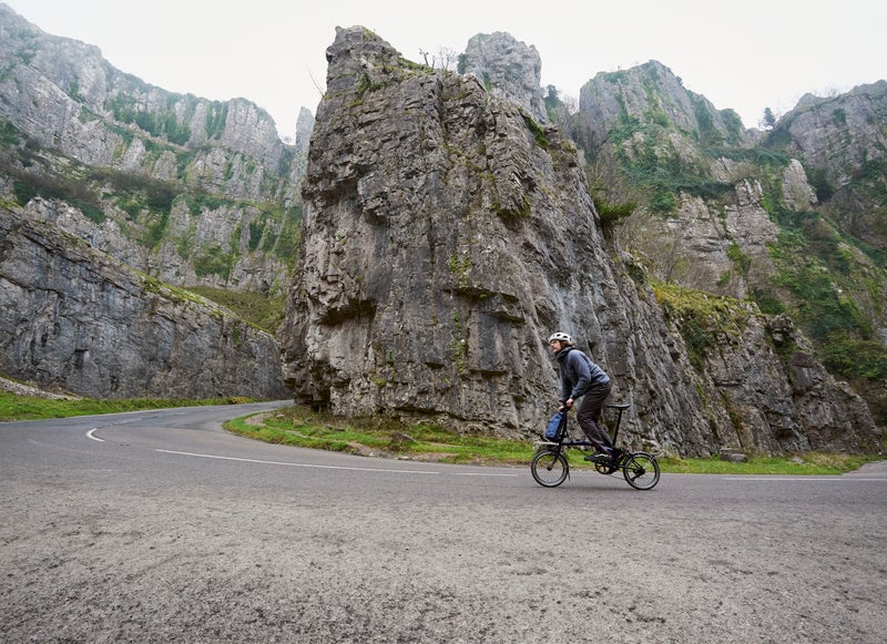 Person riding a Brompton P Line folding bike up a hill