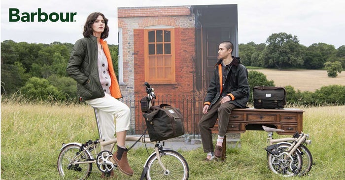 Two models posing with the Barbour x Brompton collection and special edition folding bike
