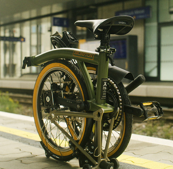 The Brompton x Bear Grylls bike folded waiting at the train station