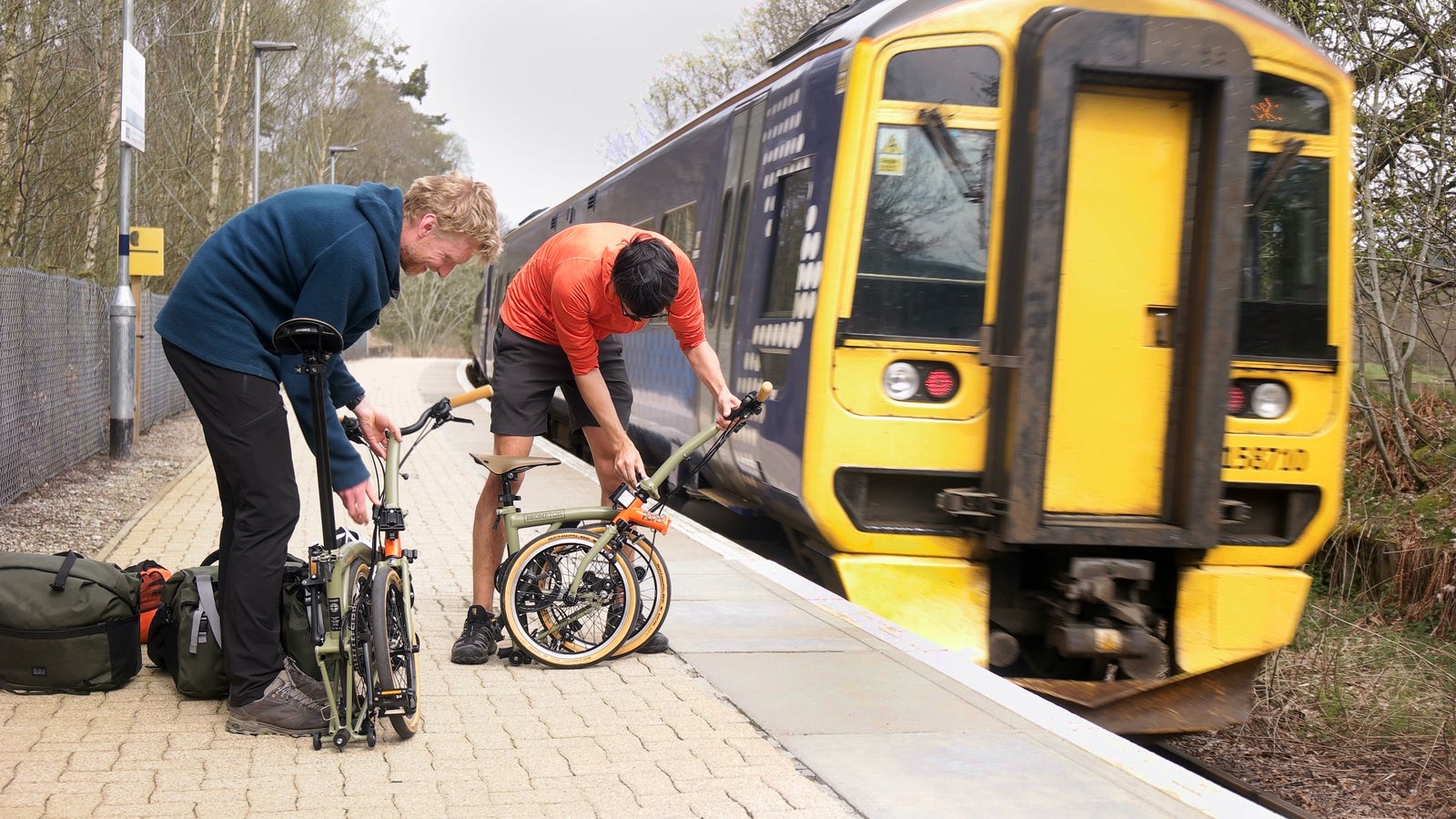 2 uomini che aprono le bici Brompton su una piattaforma del treno