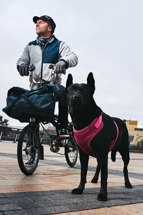 Uomo su una bici Brompton con il suo cane nero