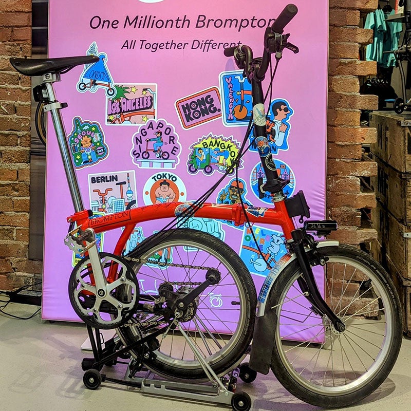 The One Millionth Brompton displayed in front of the One Millionth stickers outside Brompton Junction Paris