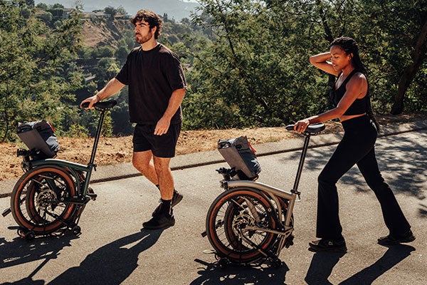 Two people rolling Brompton G Line bikes along a road