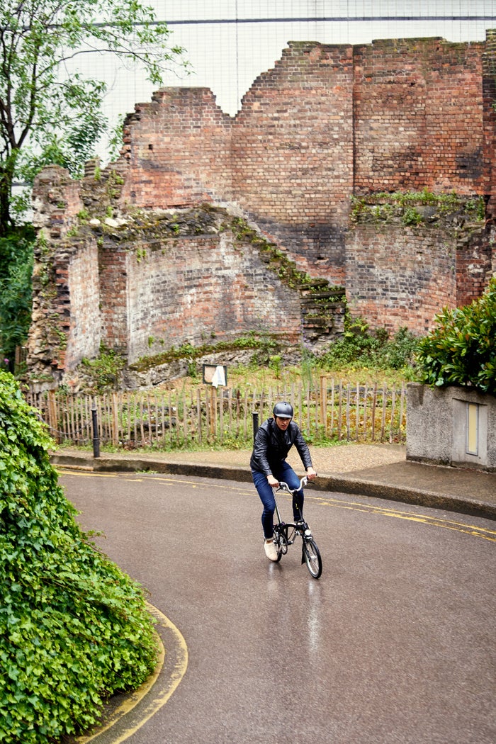 person riding brompton hire bike down a road