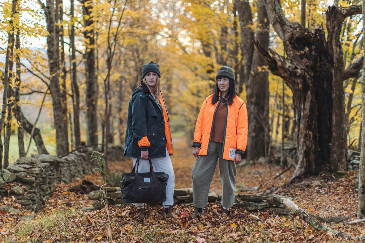 Two women on Barbour x Brompton C Lines riding through the forest in Barbour x Brompton jackets