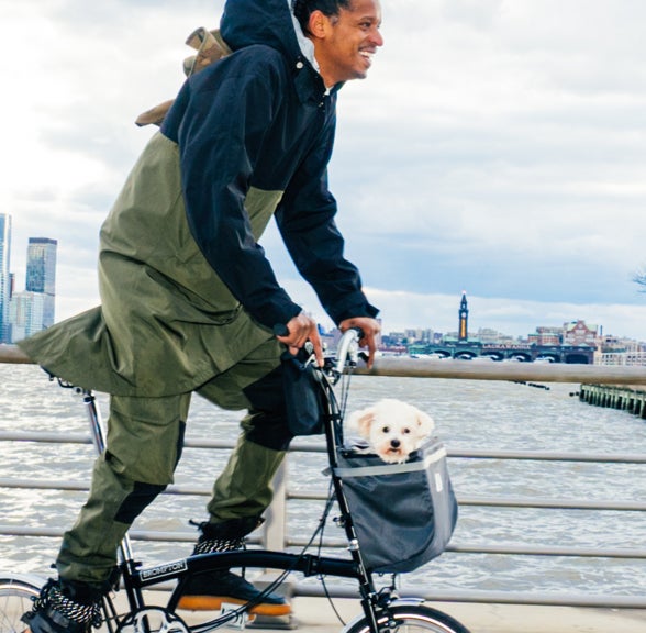 Chef Robles riding a Brompton C Line next to the Hudson with a puppy in his front carrier basket