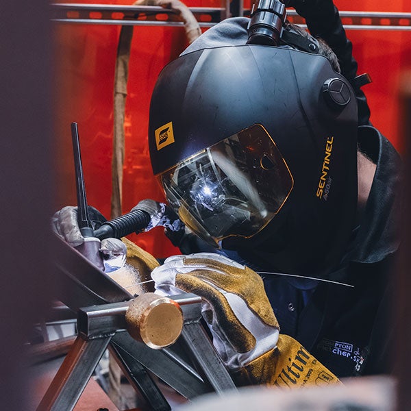 A person Tig welding a frame