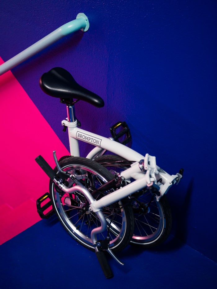 A folded Brompton A Line against a super colorful hot pink and navy blue painted wall