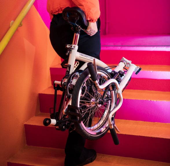 A person carrying a folded A Line up a flight of pink and orange stairs