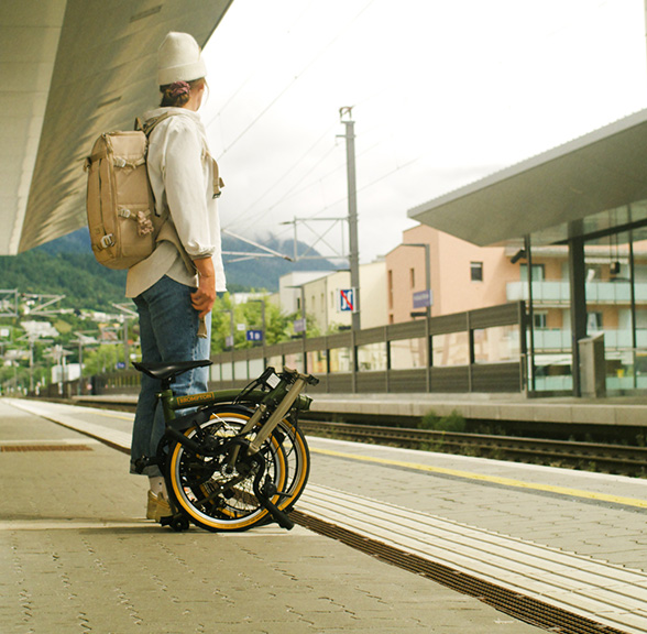 Clara Johanna with her Brompton x Bear Grylls folding bike waiting for a train