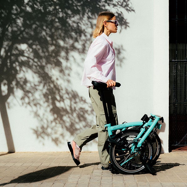 Person pushing a folded Brompton bike