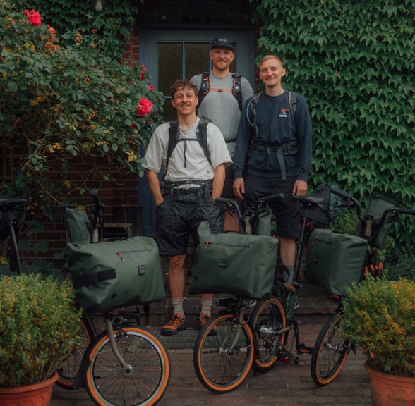 The German Roamers posing out front of a house with their Brompton x Bear Grylls folding bike