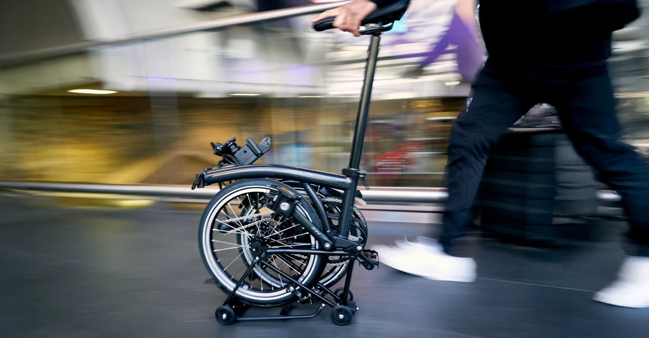Woman pushing folded Brompton bike