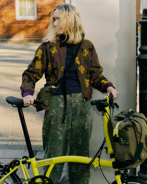 Woman stood with Brompton bike wearing Brompton x Ally Capellino bags