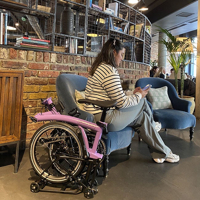 Pink bike next to women on chair
