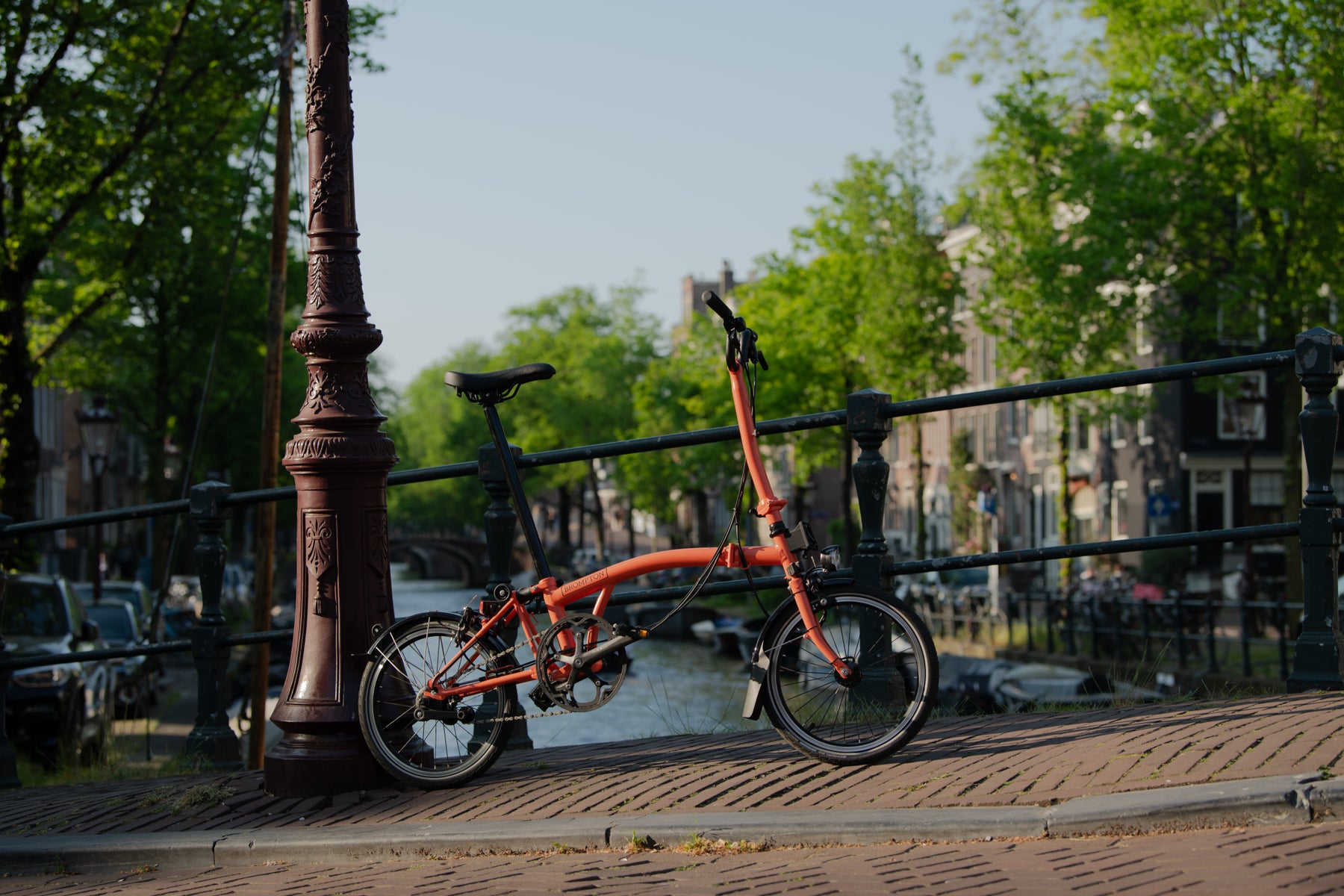 een brompton fiets leunend tegen een rail voor de gracht in amsterdam