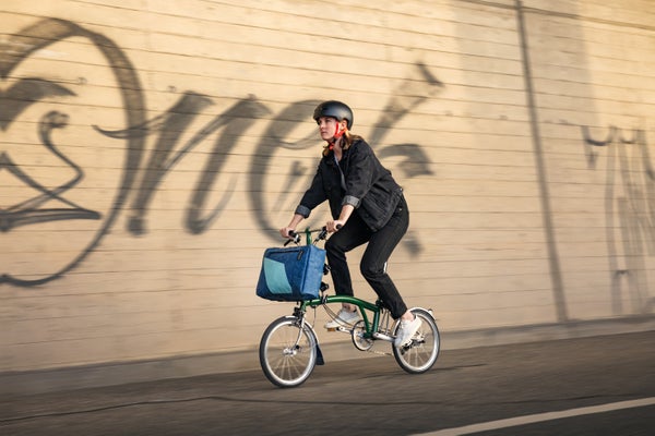 Une femme sur un vélo pliant Brompton avec un sac Freitag clipsé sur le bloc à bagages