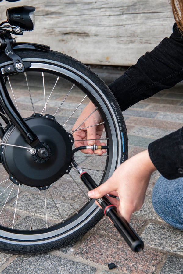 A person pumping a Brompton tyre with the Pump with Mounting Brackets