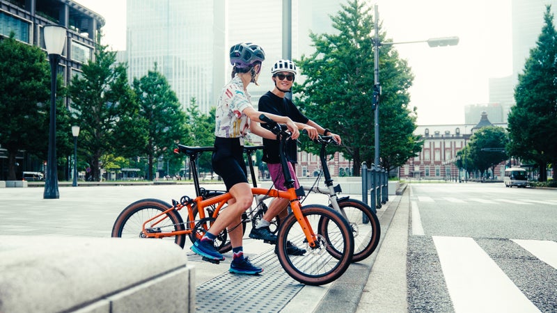 横断歩道に立つ二人。ブロンプトンGラインの自転車を携えている。
