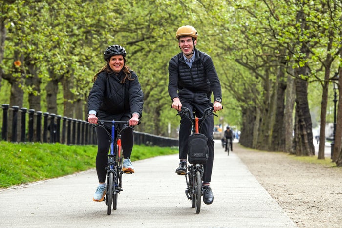 two people cycling brompton bikes through the park