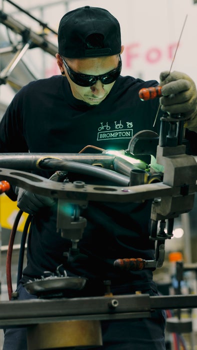 Un hombre soldando el cuadro de una bicicleta Brompton G Line