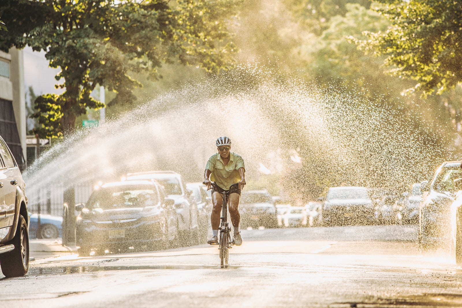 Person cycling through water fountain on a Brompton.