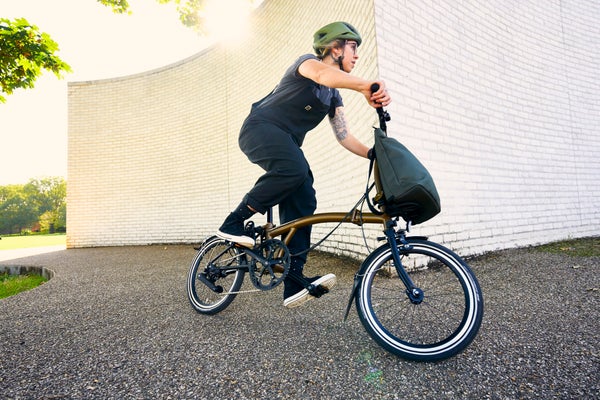 person in green helmet riding a brompton bike in bronze