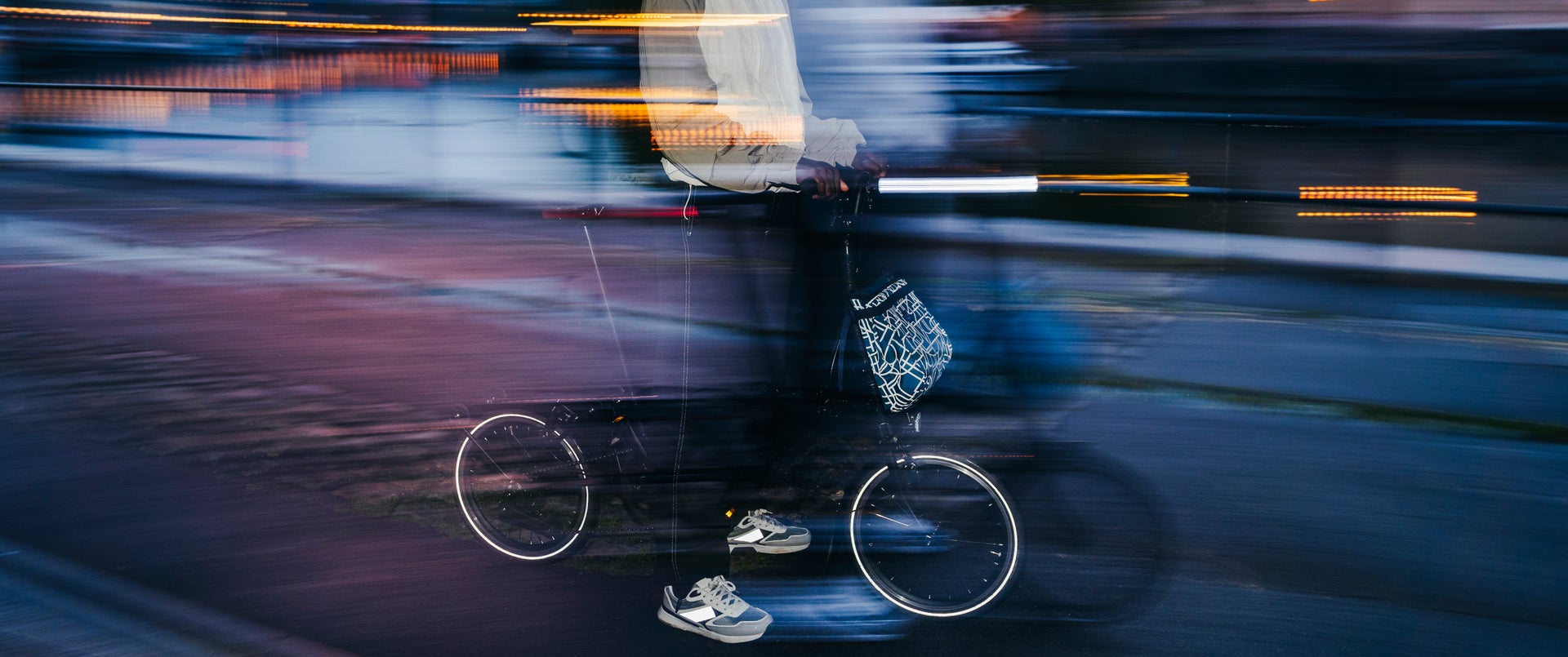 An artistic photograph of the Bright Night luggage attached to a Brompton folding bike with a Front Carrier Block
