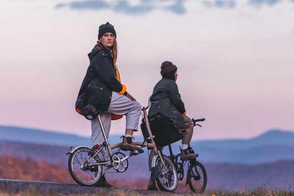 Two models posing with the Barbour x Brompton collection and special edition folding bike