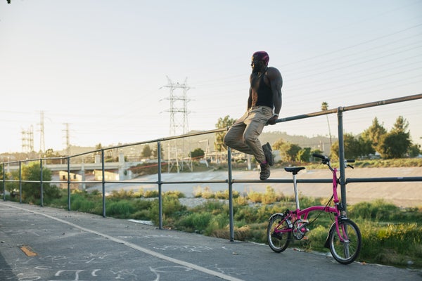 person sat on a fence with pink brompton folding bike