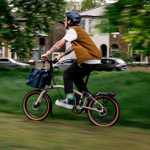 Man riding Brompton bike on grassy path