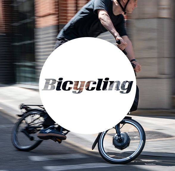 Bicycling logo in white circle over Brompton bicycle