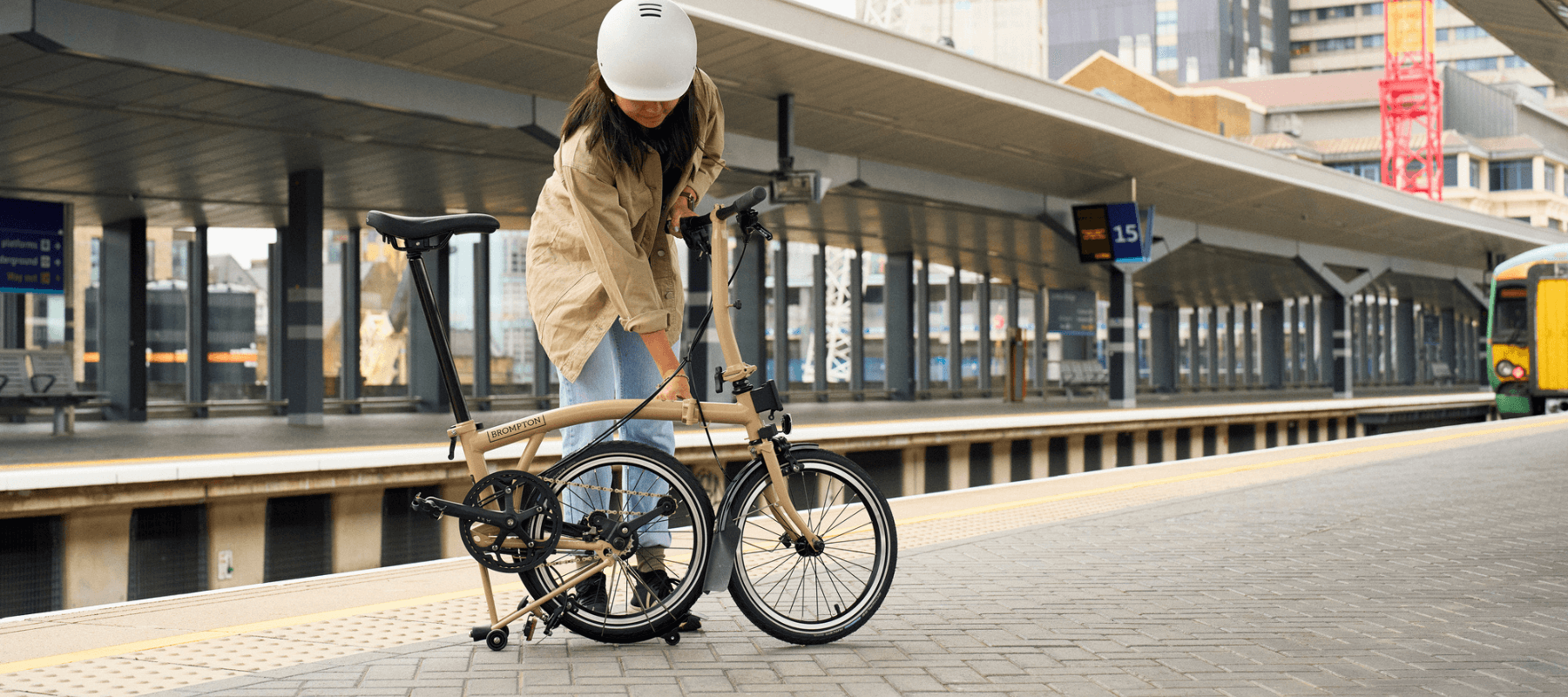 Person with a partially folded Brompton bike on a train platform