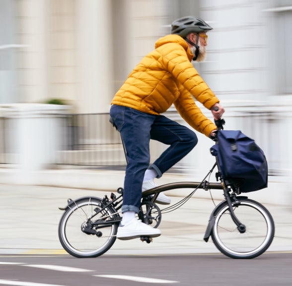 Person, die mit einem Brompton-Fahrrad durch die Stadt fährt