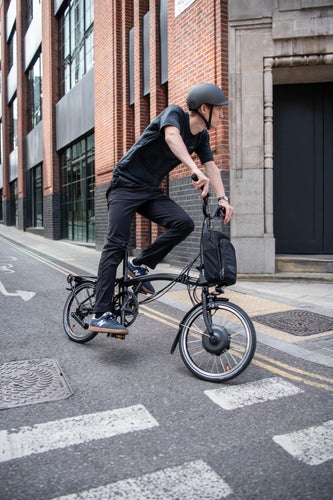 A person cycling through the streets on their Brompton Electric bike