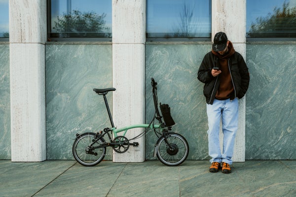 Person stood next to a matcha green Brompton bike