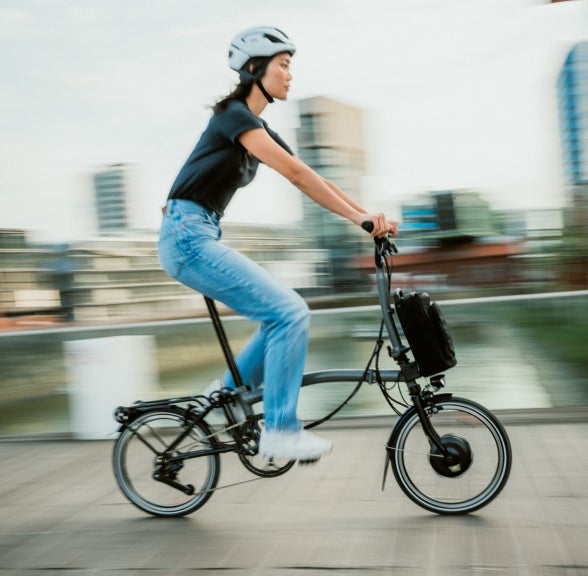 A woman riding a Brompton Electric P Line through the city